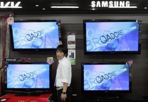 An electronics shop salesperson sells flat screen TVs of Samsung Electronics displayed at a shop in Seoul