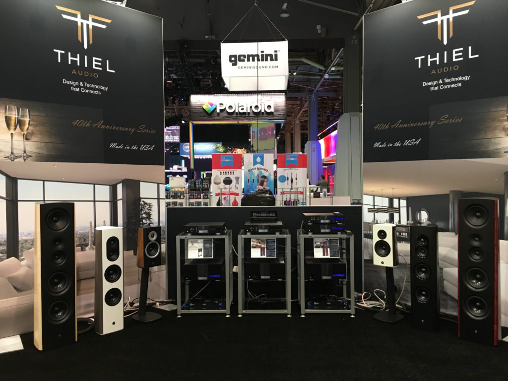 A photo from a trade show picturing the Thiel booth with lots of speakers and electronics