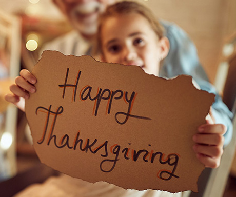 Young girl holding a Happy Thanksgiving sign